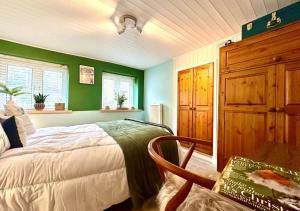 ein Schlafzimmer mit grünen Wänden, einem Bett und einem Stuhl in der Unterkunft The Bolt in Lynmouth