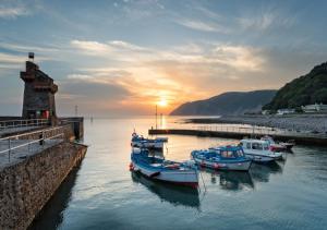 a group of boats docked in a harbor with the sunset at The Bolt in Lynmouth