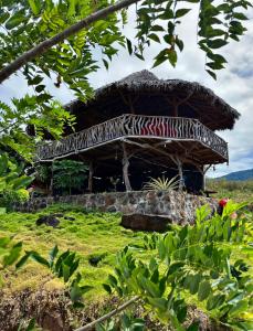 une grande cabane avec un toit en paille dans un champ dans l'établissement Hostel & Camping Sol Y Luna Ometepe, à Balgue