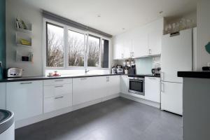 a kitchen with white cabinets and a large window at Large villa with garden in Suresnes - Welkeys in Suresnes