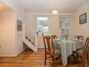 una sala da pranzo con tavolo, sedie e scala di Clements Cottage a Paignton