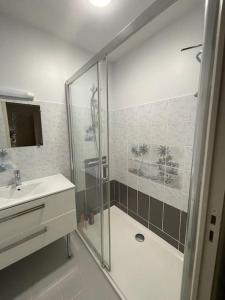 La salle de bains blanche est pourvue d'une douche et d'un lavabo. dans l'établissement Location maison saisonnière, à Pleurtuit