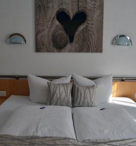 a bed with two white pillows and a heart painting at Apart Anna in Ischgl