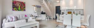 a living room with white furniture and a staircase at Prestige House Apartament - 2 sypialnie z ogródkiem i basenem in Pobierowo