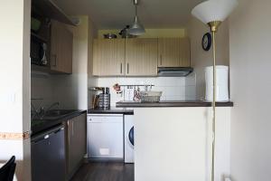 een keuken met witte apparaten en houten kasten bij Résidence Serias - 3 Pièces pour 6 Personnes 484 in Germ
