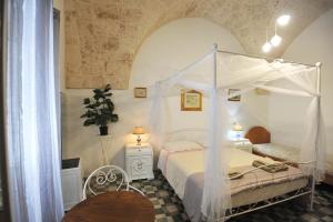 a bedroom with a canopy bed and a table at B&B CASAVACANZE CHIESA MADRE in Carovigno