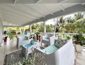 een veranda met witte stoelen, tafels en palmbomen bij Villa Lu-Ja 