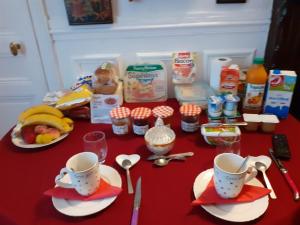 einen roten Tisch mit Tassen, Löffeln und Essen in der Unterkunft Marie et Igor in Paris