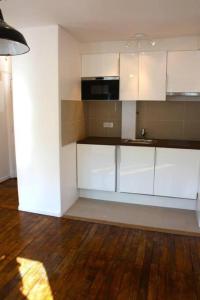 een lege keuken met witte kasten en een houten vloer bij Beautiful 1 bedroom in Le Marais in Parijs