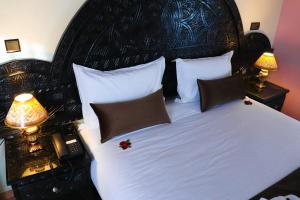 a bedroom with a white bed with two lamps and a phone at Hôtel Riad Salam Agadir in Agadir