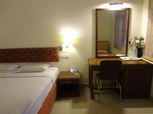 a bedroom with a bed and a desk and a mirror at Hotel Malainn in Chennai