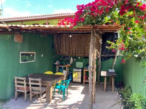 una mesa y sillas frente a un edificio verde con flores en Caju com Mel, en Moreré