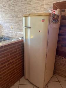 um frigorífico branco numa cozinha com uma parede de tijolos em Kitinet com 01 quarto em Vila Velha