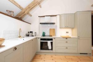 a kitchen with white cabinets and a sink and an oven at Spacious country retreat in the heart of Devon. in Crediton