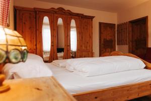 a bedroom with a large white bed with wooden cabinets at Unertl Bräustüberl Gästehaus in Haag in Oberbayern