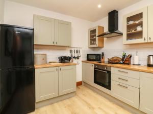 a kitchen with white cabinets and a black refrigerator at Blue Bay in Lynton