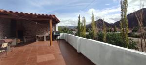 Un balcón de una casa con una valla y árboles en Hostal Cadena en Tupiza