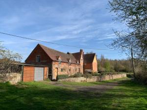 an old brick house with a fence in front of it at Unique 17c listed Barn in a Shropshire hamlet. in Albrighton