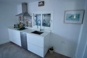 cocina blanca con lavabo y espejo en Apartamento Narcisa en El Golfo