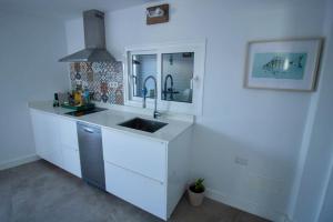 Una cocina blanca con fregadero y espejo. en Apartamento Narcisa, en El Golfo