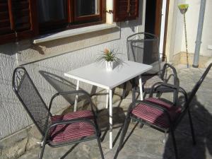 una mesa blanca con dos sillas y una planta en ella en Apartmani Sobe KATICA, en Cres