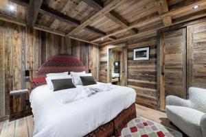 um quarto com uma cama grande num quarto com paredes de madeira em Résidence Nanook - Chalets pour 15 Personnes 444 em Saint-Martin-de-Belleville