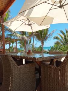 ein Tisch mit Stühlen und ein Sonnenschirm am Strand in der Unterkunft Kalua Plateritos in Plateritos