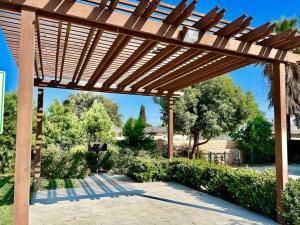 una pérgola de madera en un patio con árboles y arbustos en Up to 20% off weekly stay 3BR 2.5 miles to airport, en Ontario