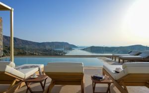a pool with lounge chairs and a view of the ocean at Elounda Bright Villa in Elounda +38 photos