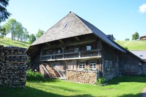 een oud houten huis met een stenen muur bij Sonnerhof Hofsgrund in Oberried