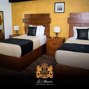 a hotel room with two beds with a crest on them at Hotel Boutique La Mansión Guadalajara in Guadalajara