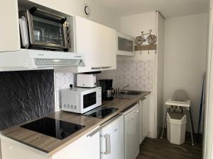a kitchen with white cabinets and a microwave at Résidence Royal Peyragudes Mp - T2/6pers -ROYAL 31B- Peyresourde MAE-2954 in Germ