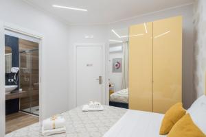MarGab Guest House في نابولي: غرفة نوم بسرير ابيض وخزانة صفراء