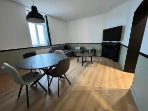een woonkamer met een tafel en stoelen en een bank bij L’émeraude : vue mer - MALO’Cation in Duinkerke