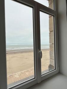 een raam met uitzicht op het strand bij L’émeraude : vue mer - MALO’Cation in Duinkerke