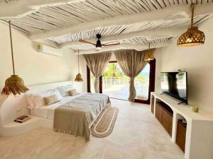 a bedroom with a bed and a flat screen tv at Unique Beachfront Casa Kyma, Pool, San Crisanto, Yucatan in San Crisanto +44 photos