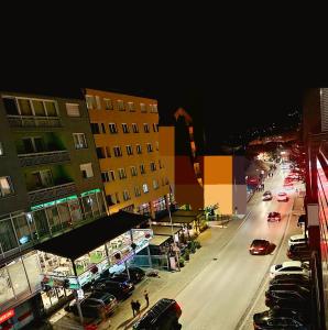 uma rua da cidade à noite com carros e edifícios em Apartman-Stan em Bugojno