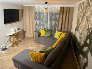 a living room with a gray couch and yellow pillows at Spa Aphrodite, Wohlfühlen und Wellness mit Privatsphäre, sowie Homeoffice Arbeitsplatz mit schnellem 250 Mbit WLAN in Aidlingen