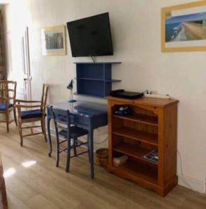 ein Wohnzimmer mit einem Tisch und einem TV an der Wand in der Unterkunft Location cure ou vacances dans maison charentaise centre ville in Saujon