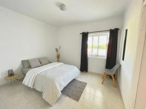 a white bedroom with a bed and a window at Casa da praia in Aljezur