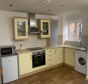 een keuken met gele kasten en een wasmachine en droger bij Shepshed 2 Bedroom Apartment in Shepshed