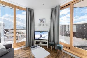 a living room with a tv and large windows at Résidence Machu Pichu - 3 Pièces pour 6 Personnes 244 in Val Thorens