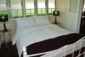 a white bed in a room with two windows at Ocean Serenity in Mission Beach