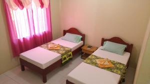 two twin beds in a room with pink curtains at Villa Almedilla Pension House in Panglao Island