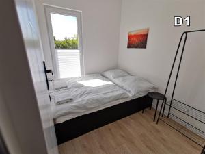 a small bed in a room with a window at DM DOMKI Kościelna 54 in Mielno