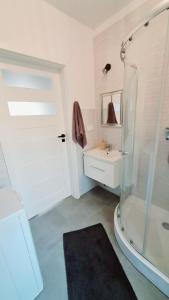 a white bathroom with a shower and a sink at Fiszka in Pobierowo