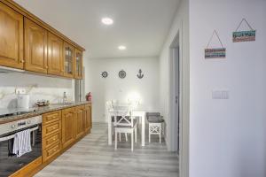 a kitchen with wooden cabinets and a table with chairs at Cantinho a Sul II - Costa Nova in Gafanha da Encarnação