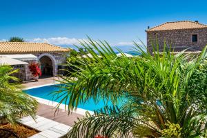 a villa with a swimming pool and palm trees at LIOKRINA country living villas & suites in Koroni