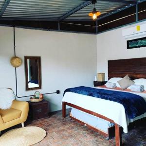 1 dormitorio con cama, silla y espejo en cabaña las chachalacas,hermoso espacio natural, en Colima