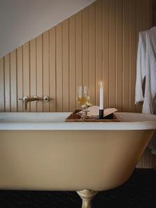 a bath tub with a candle and wine glasses at Dvele Inn in St. John's